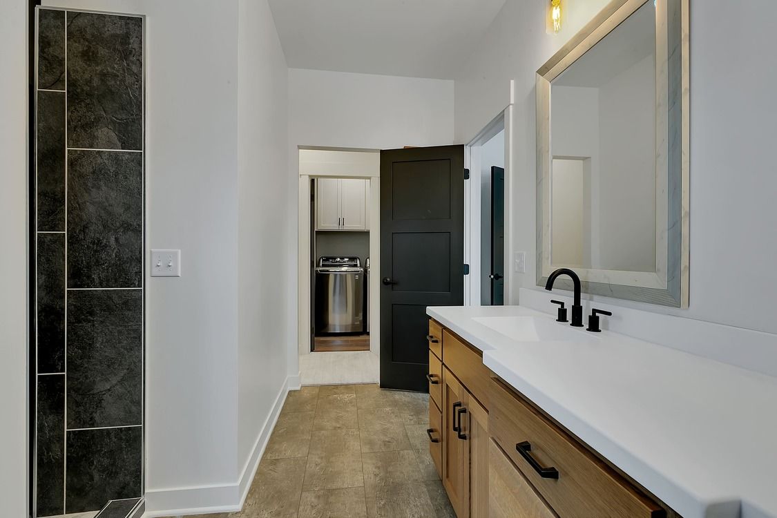 A bathroom with a sink , mirror and walk in shower.