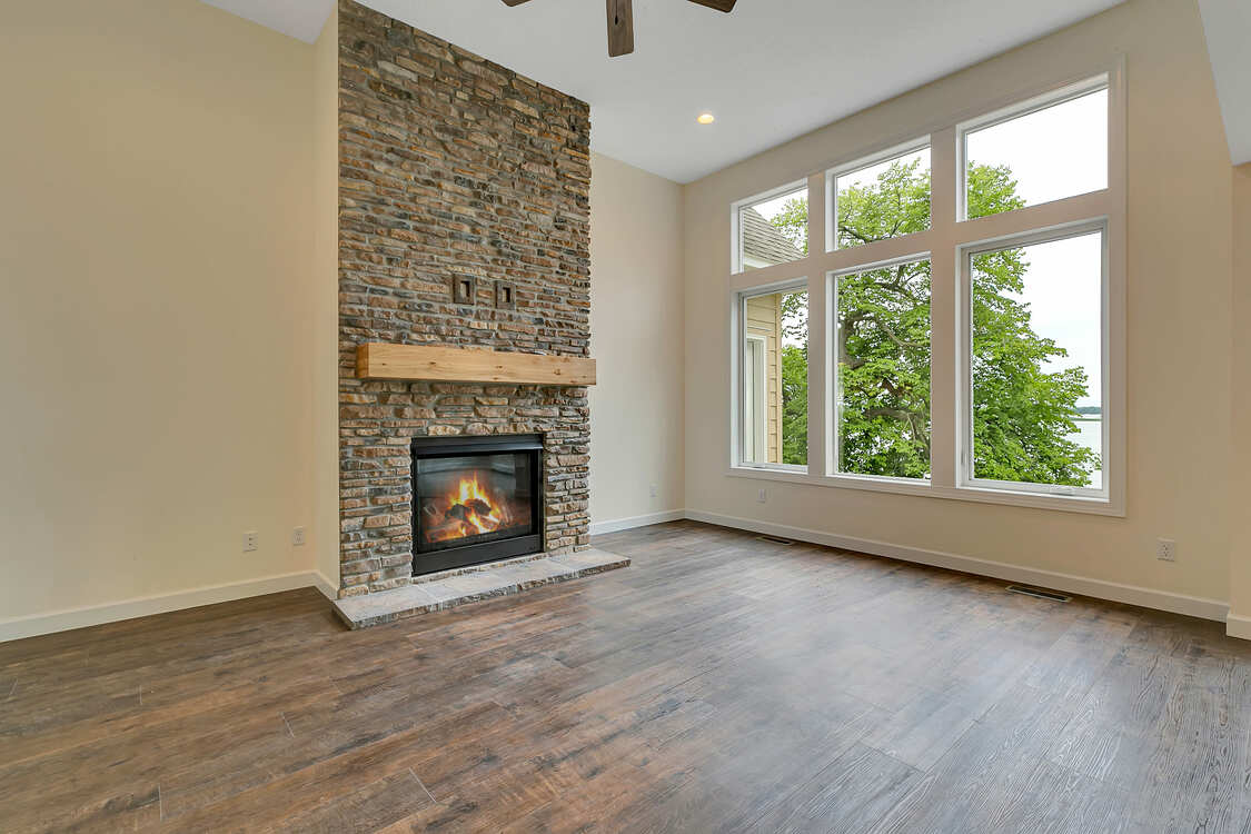 An empty living room with a fireplace and lots of windows.