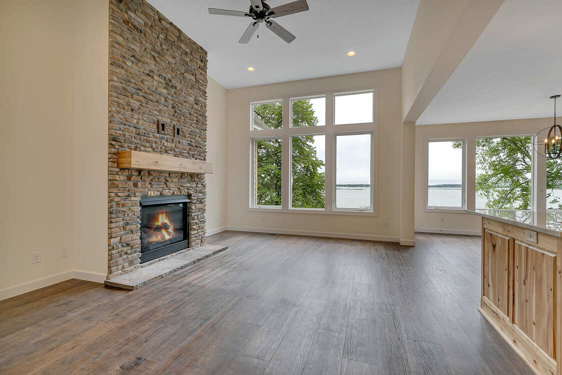 An empty living room with a fireplace and a ceiling fan.