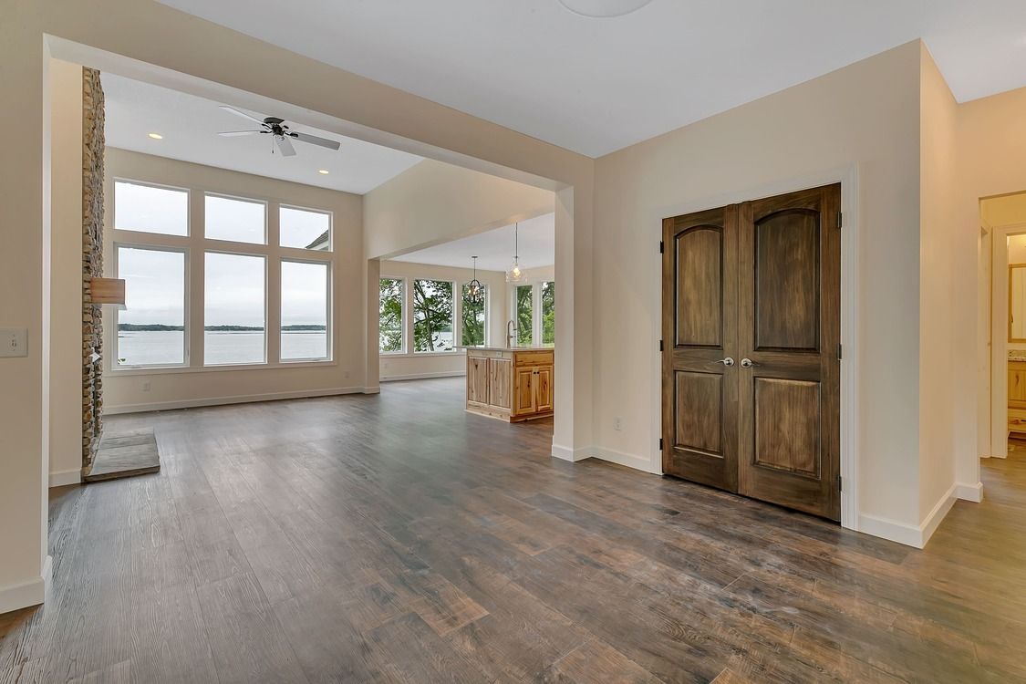 An empty living room with hardwood floors and a view of a lake.