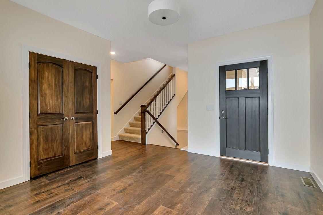 An empty room with hardwood floors and stairs in the background.