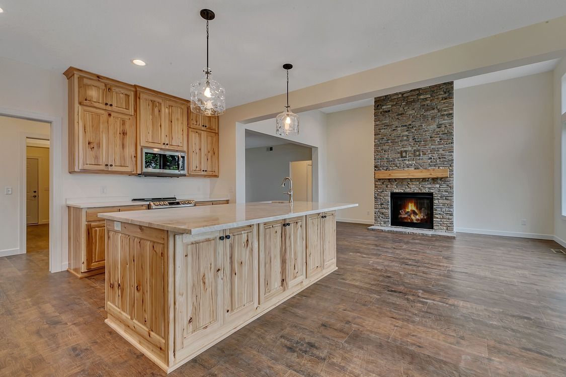 An empty kitchen with wooden cabinets and a fireplace.