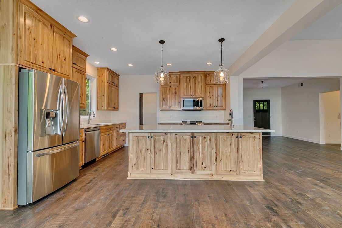 A kitchen with wooden cabinets , stainless steel appliances , and a large island.