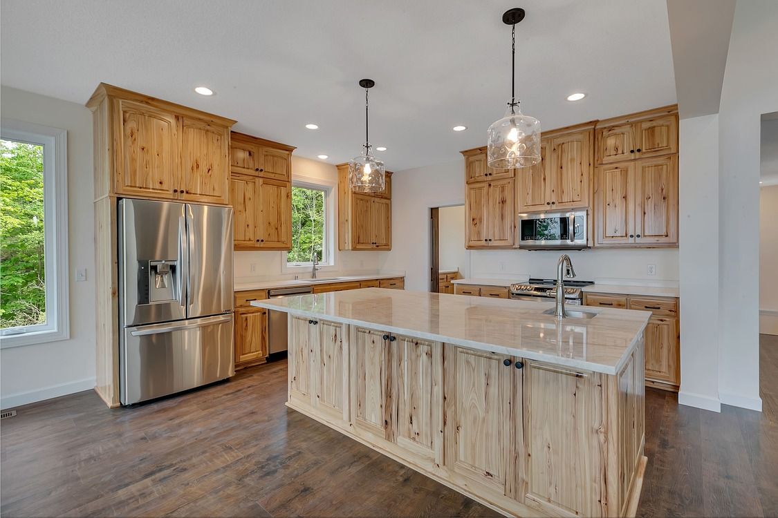 A kitchen with wooden cabinets , stainless steel appliances , and a large island.