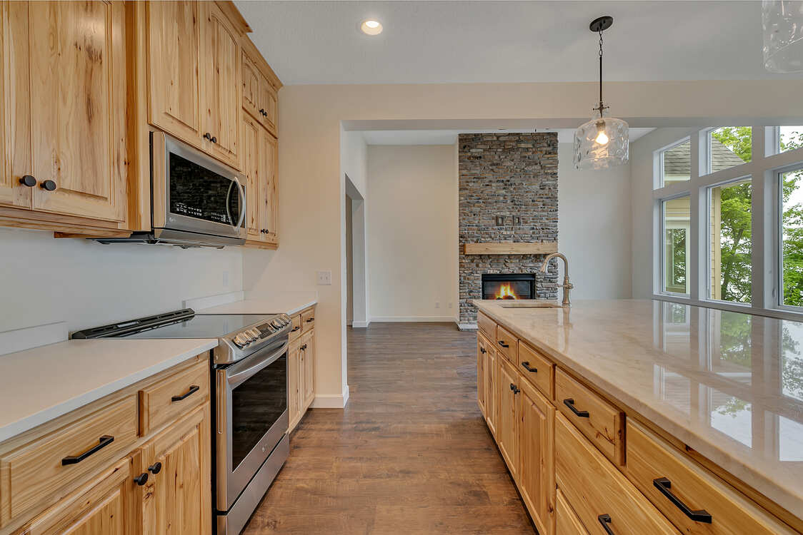 A kitchen with wooden cabinets , stainless steel appliances , and a large island.