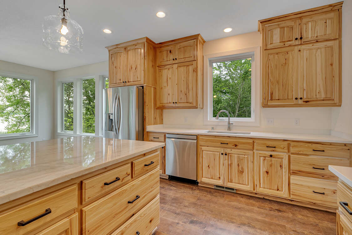 A kitchen with wooden cabinets , granite counter tops , stainless steel appliances and a large island.