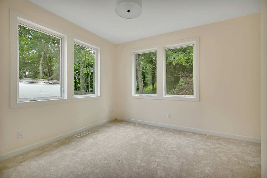 An empty room with three windows and a carpeted floor.