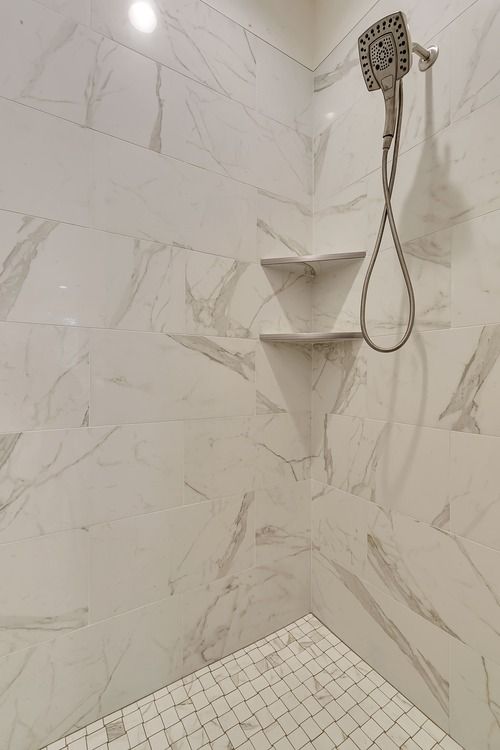 A shower with a shower head and shelves on the wall.