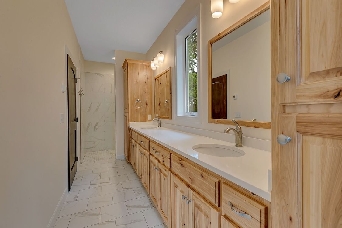 A bathroom with two sinks , a mirror and a walk in shower.