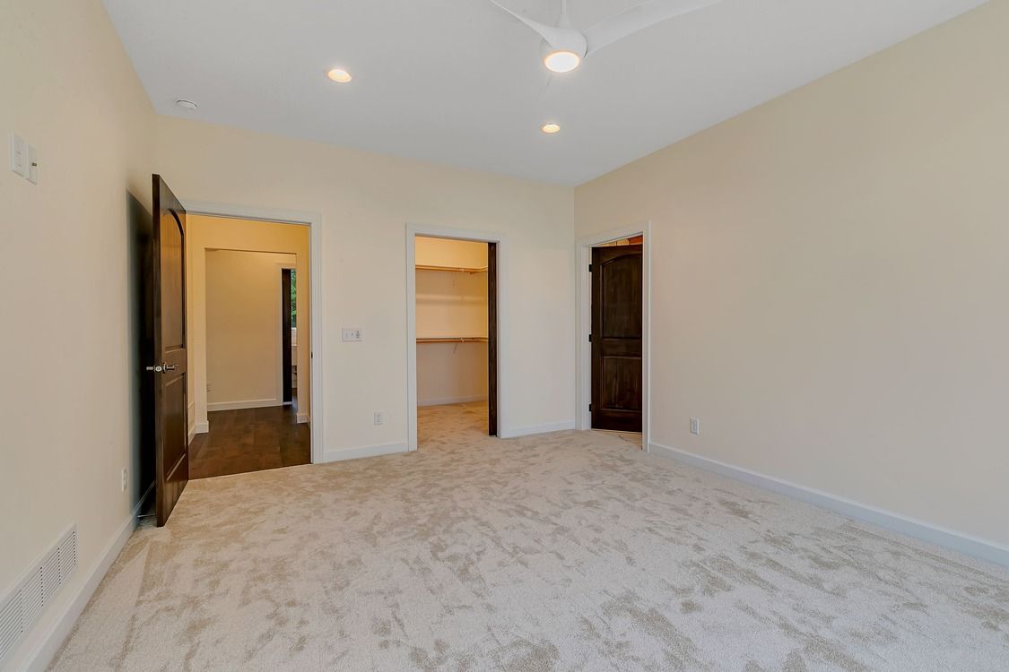 An empty bedroom with a ceiling fan and a walk in closet.