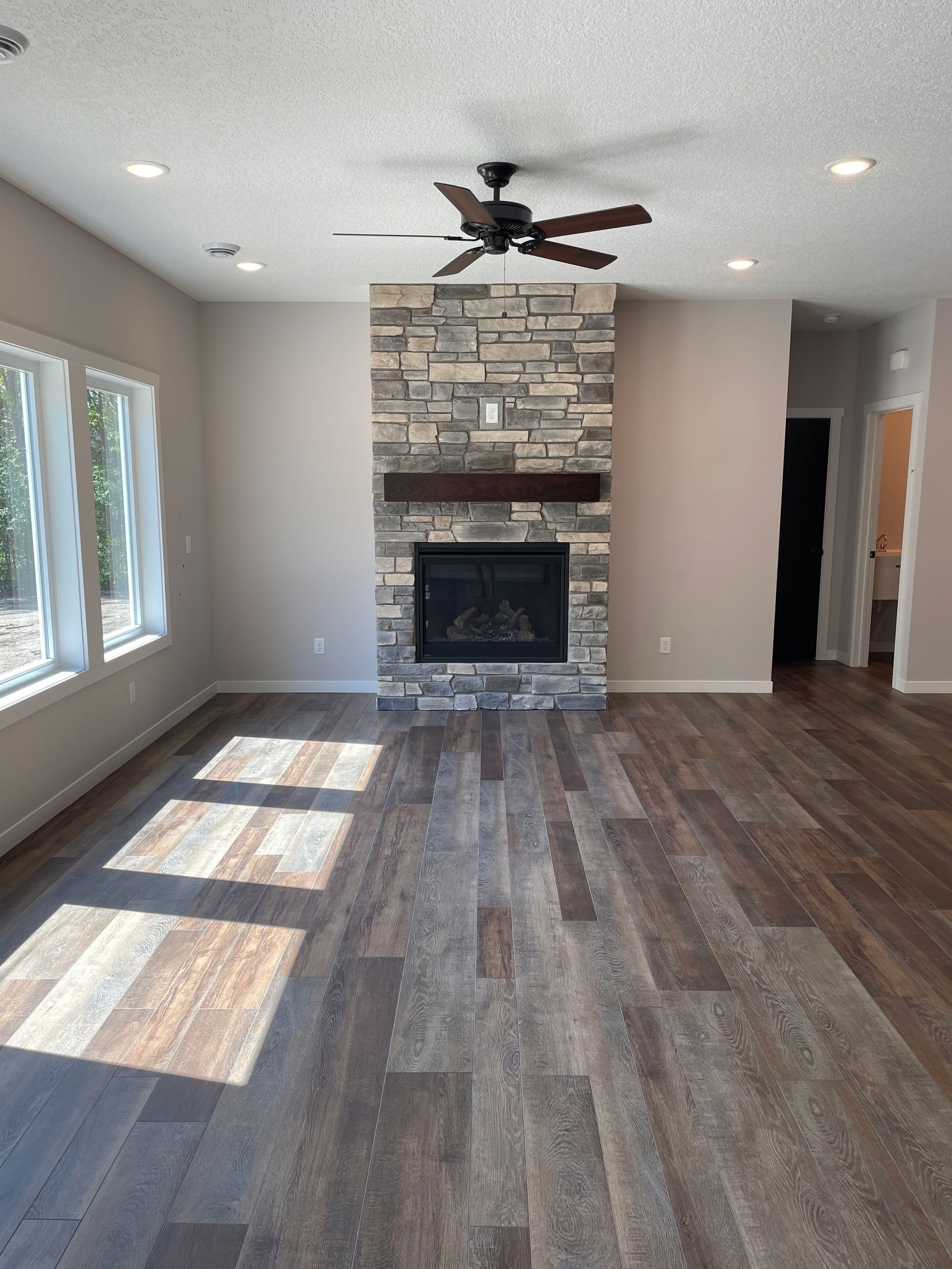 A living room with a fireplace and a ceiling fan.