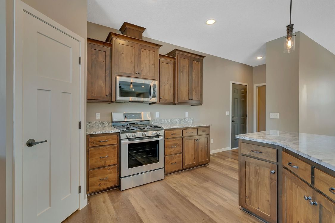 A kitchen with wooden cabinets , stainless steel appliances , and granite counter tops.