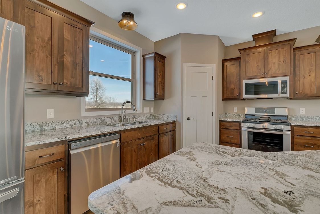 A kitchen with granite counter tops , stainless steel appliances , and wooden cabinets.