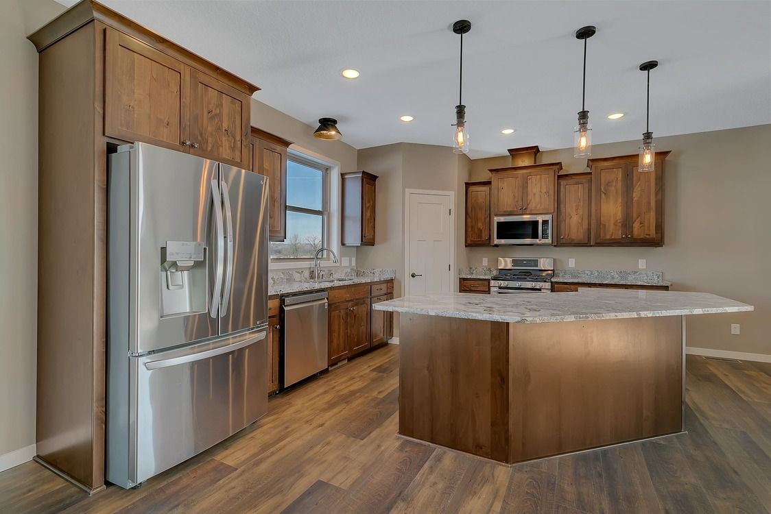 A kitchen with stainless steel appliances , wooden cabinets , and a large island.