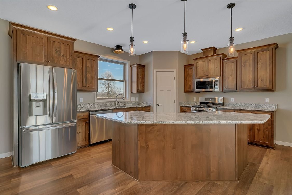 A kitchen with wooden cabinets , stainless steel appliances , and a large island.
