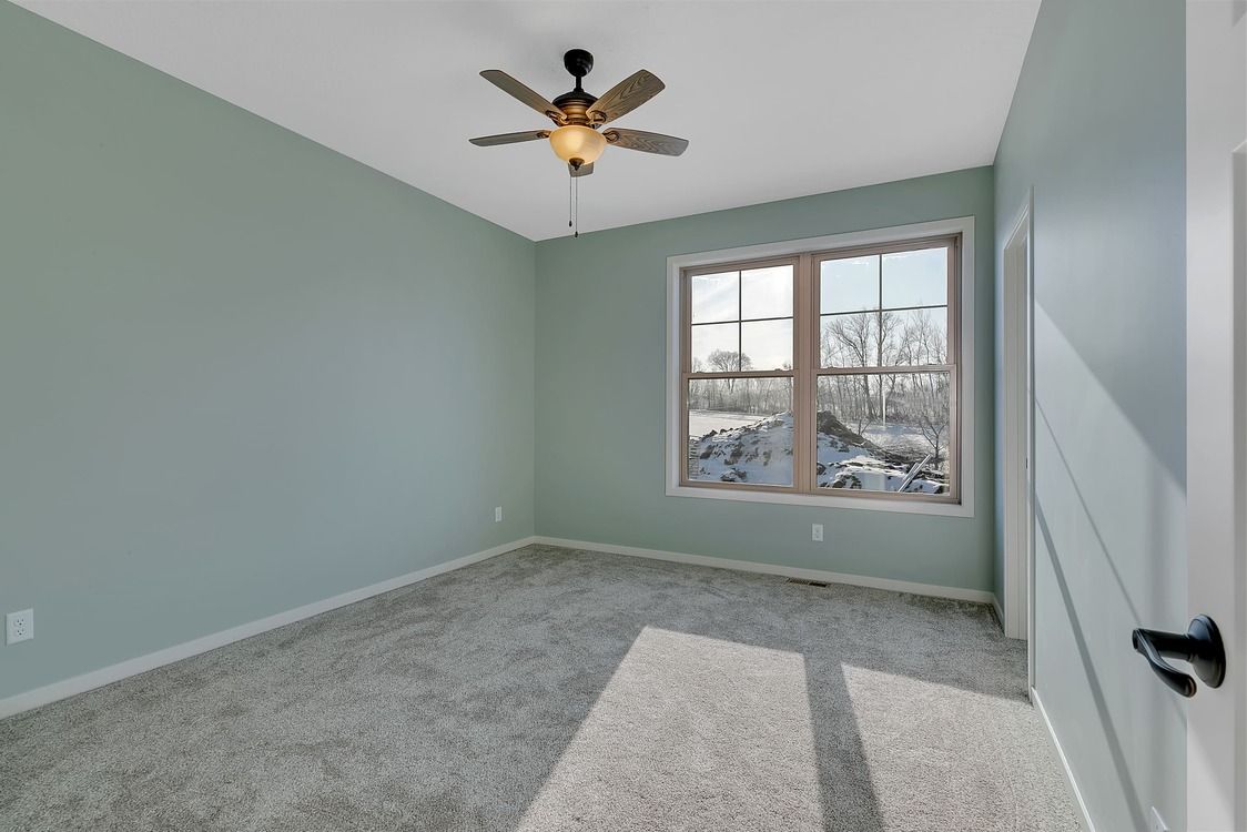 An empty bedroom with a ceiling fan and a window.