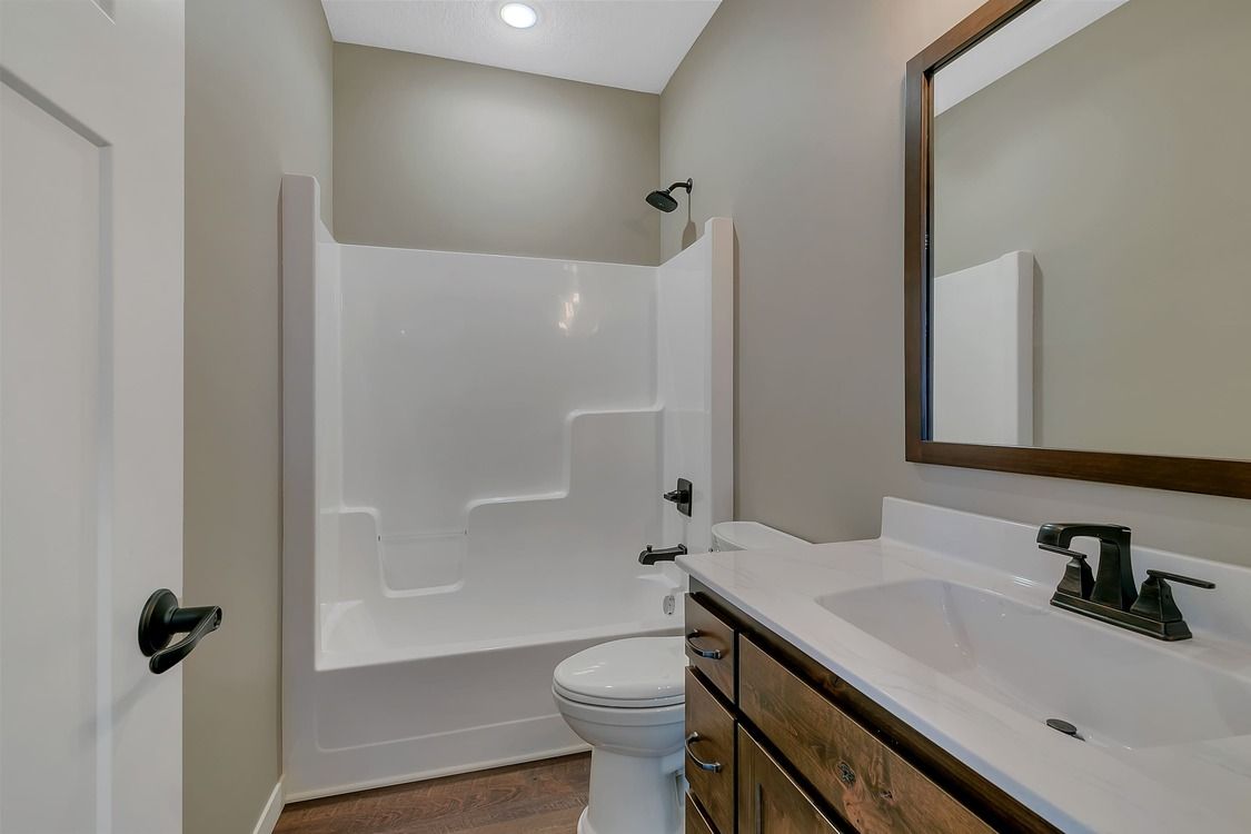 A bathroom with a toilet , sink , shower and mirror.