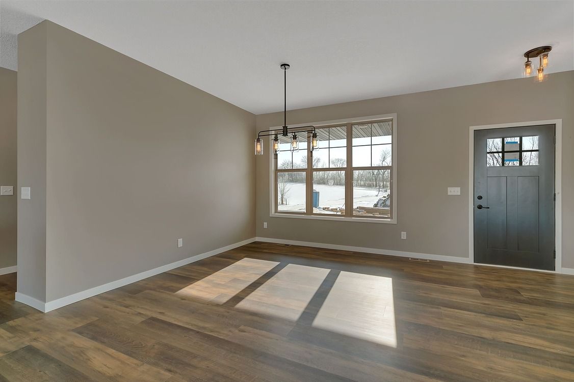 An empty living room with hardwood floors and a large window.
