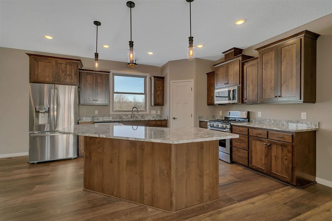 A kitchen with wooden cabinets , stainless steel appliances , and a large island.