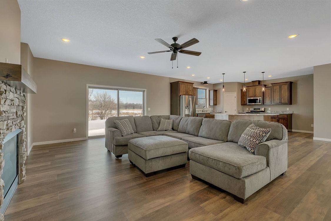 A living room with a large sectional couch and a ceiling fan.