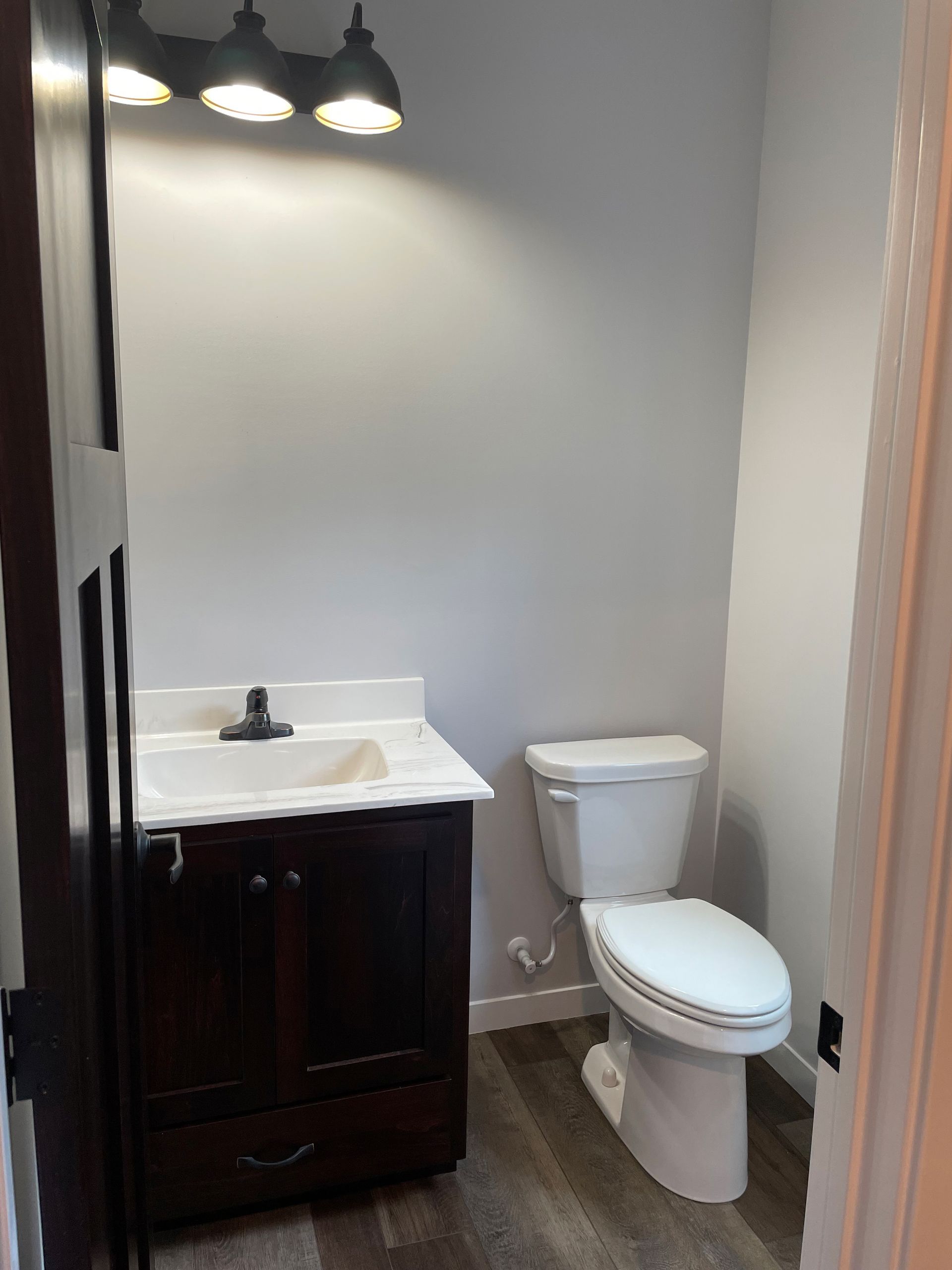 A bathroom with a toilet , sink , and light fixture.