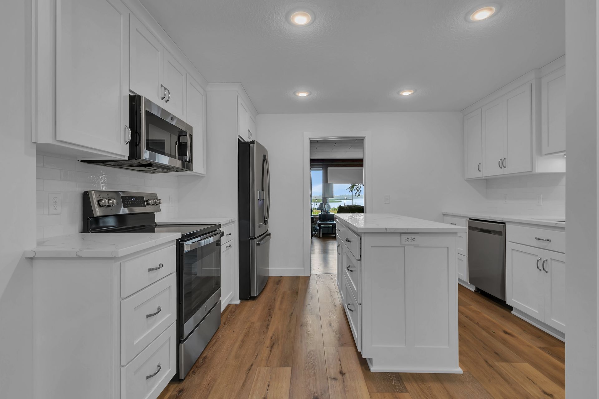 A kitchen with white cabinets , stainless steel appliances , and hardwood floors.