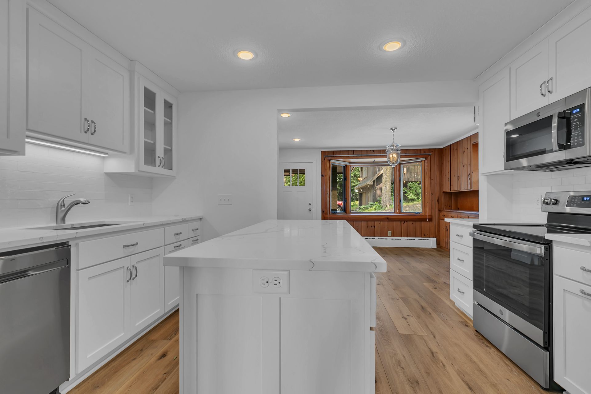 A kitchen with white cabinets , stainless steel appliances , and a large island.