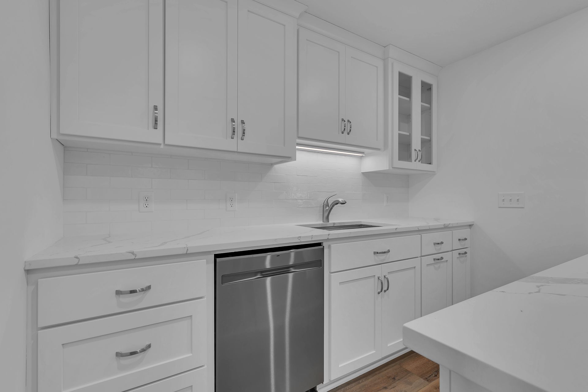 A kitchen with white cabinets , stainless steel appliances , a sink , and a dishwasher.