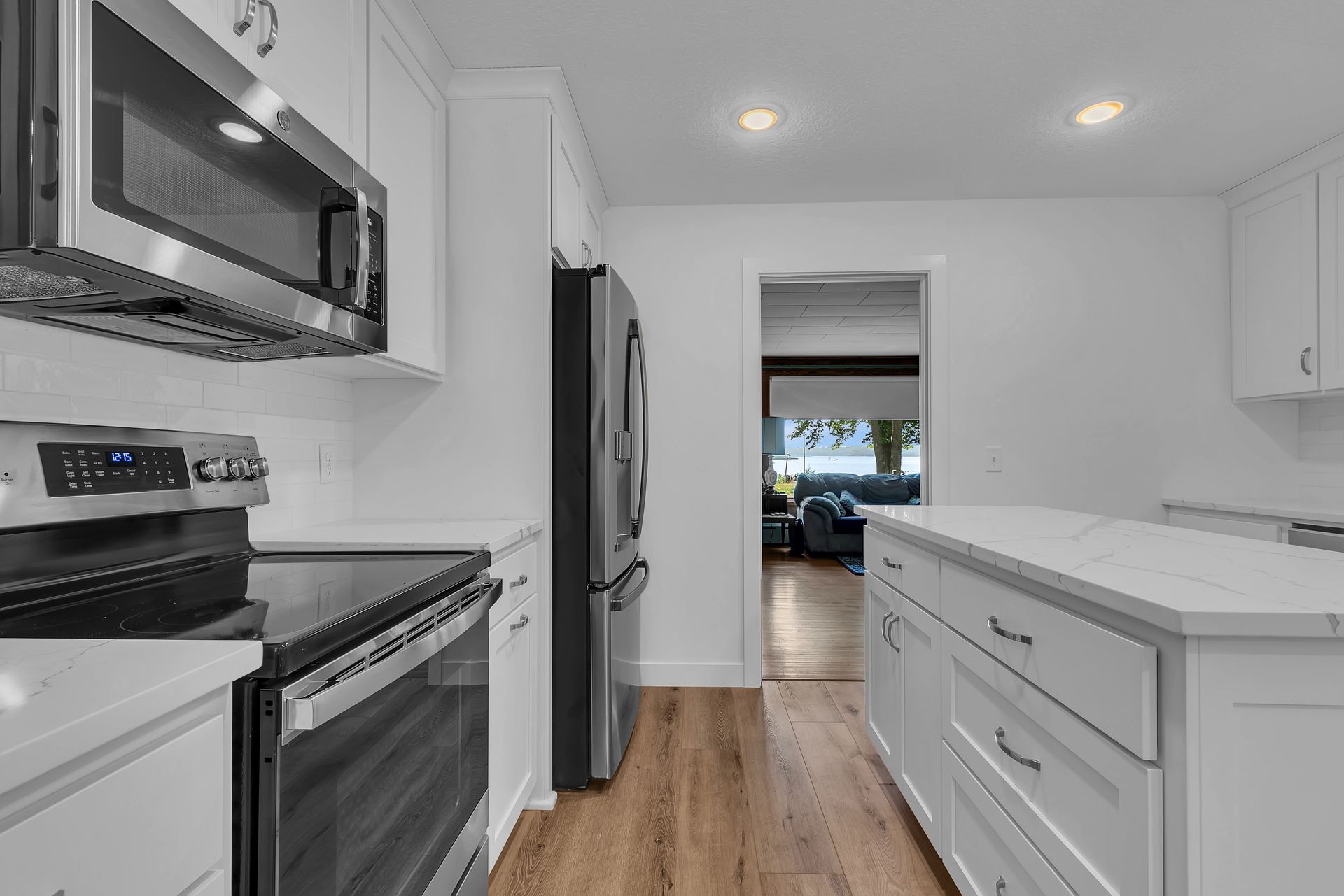 A kitchen with white cabinets , a stove , a refrigerator , and a microwave.