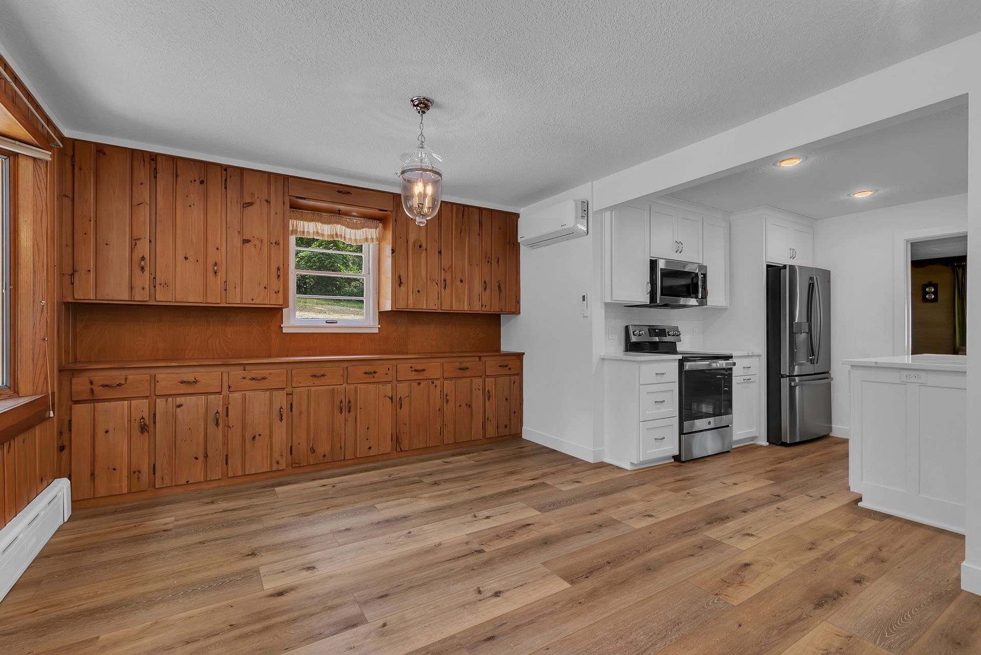 An empty kitchen with wooden cabinets and hardwood floors.