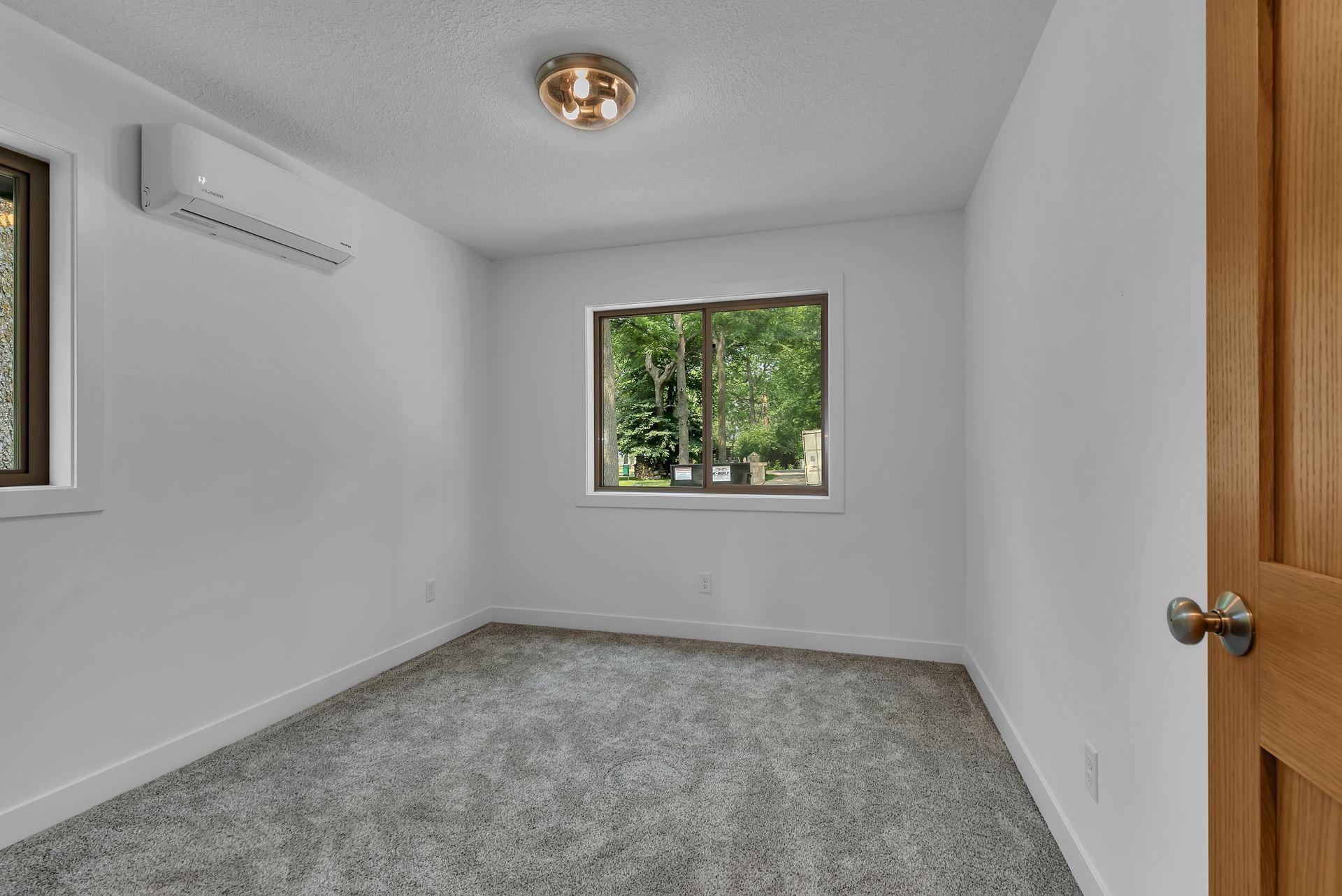 An empty bedroom with a carpeted floor and two windows.