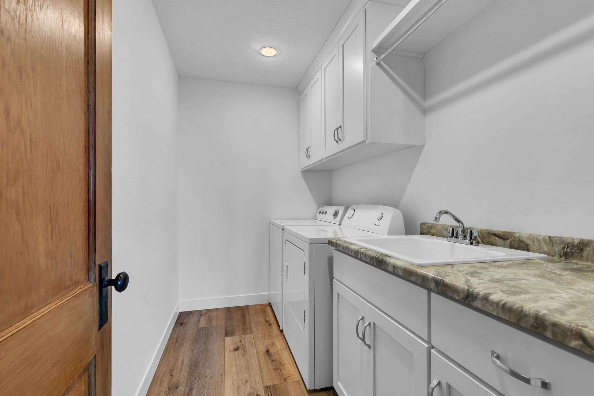 A laundry room with a washer and dryer , sink , and cabinets.