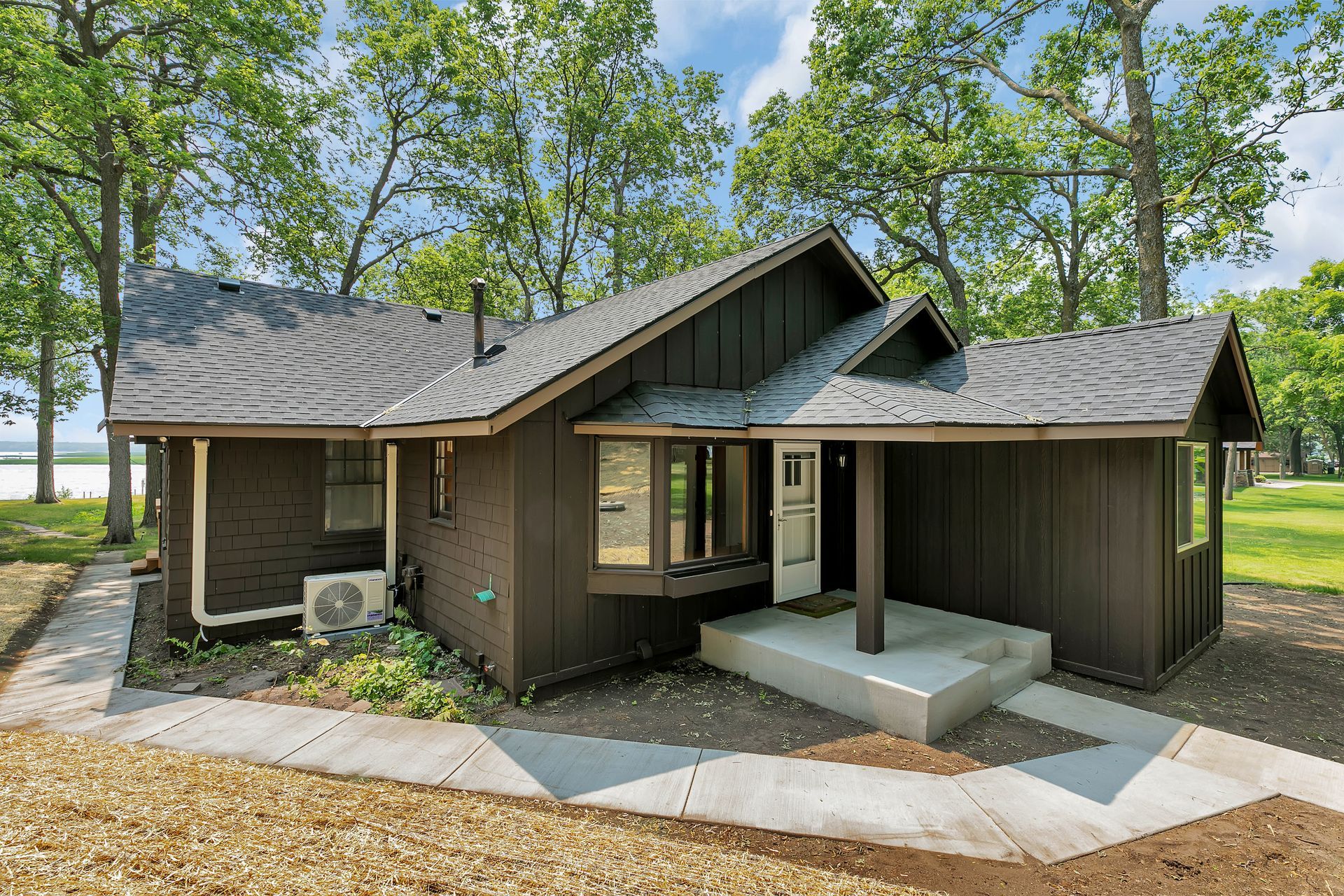 A house with a walkway leading to it and trees in the background