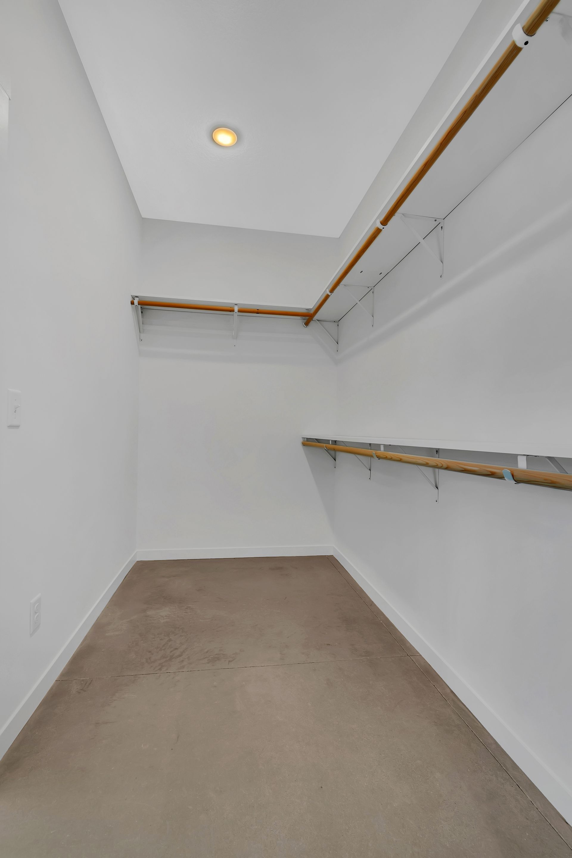 An empty walk in closet with shelves and a light on the ceiling.