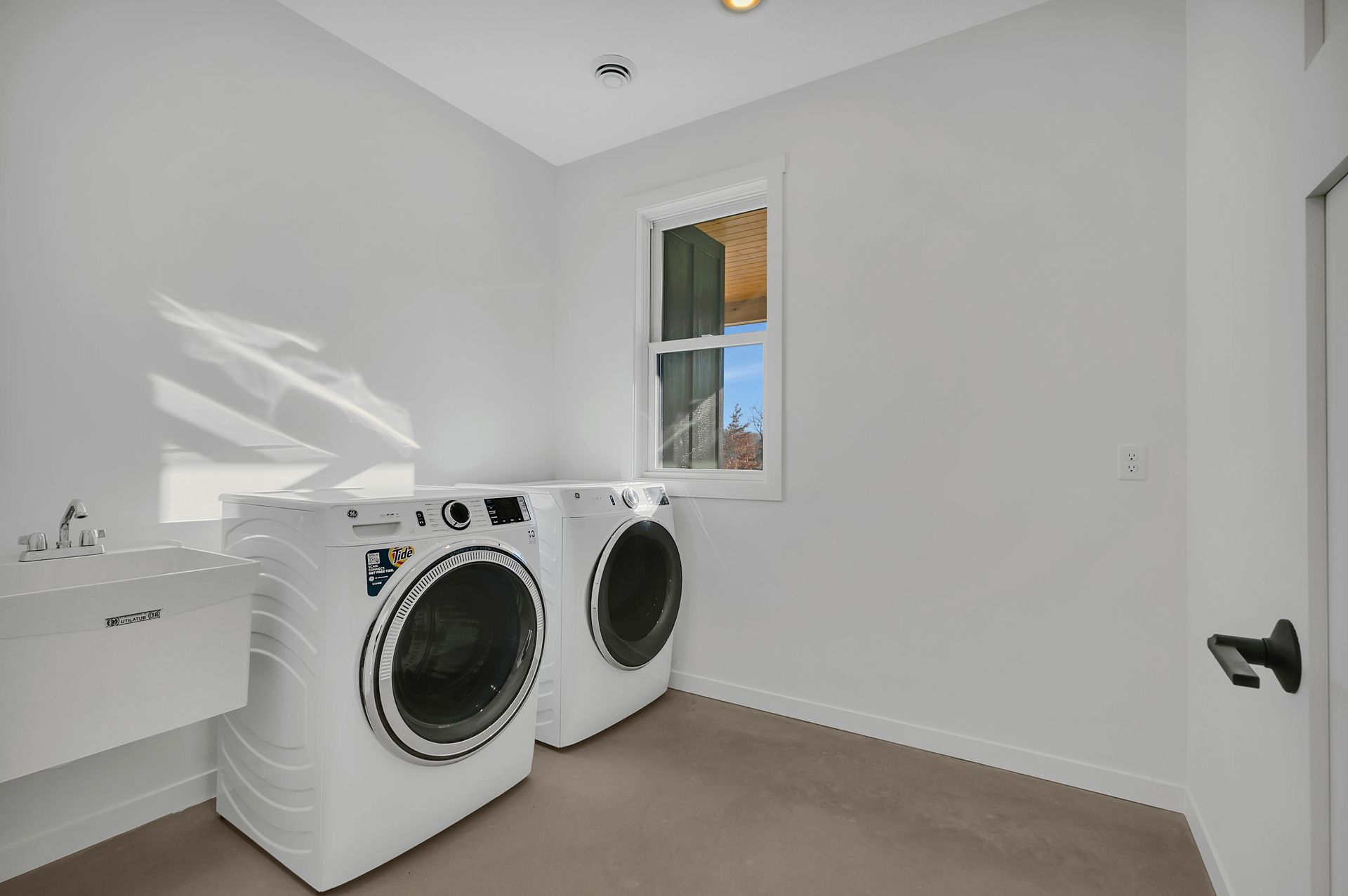 A laundry room with a washer and dryer and a window.