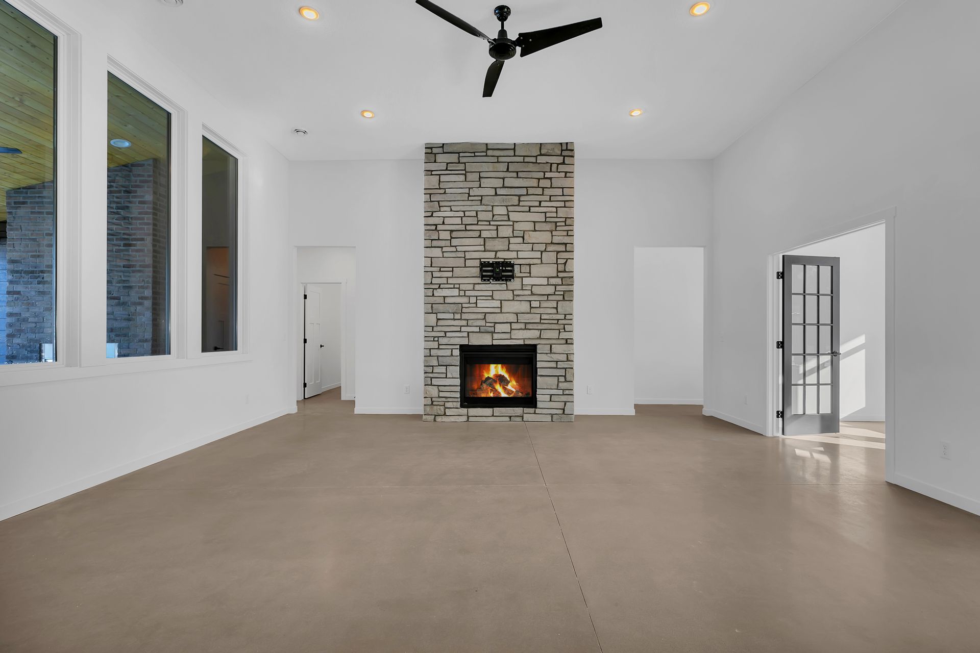 An empty living room with a fireplace and a ceiling fan.