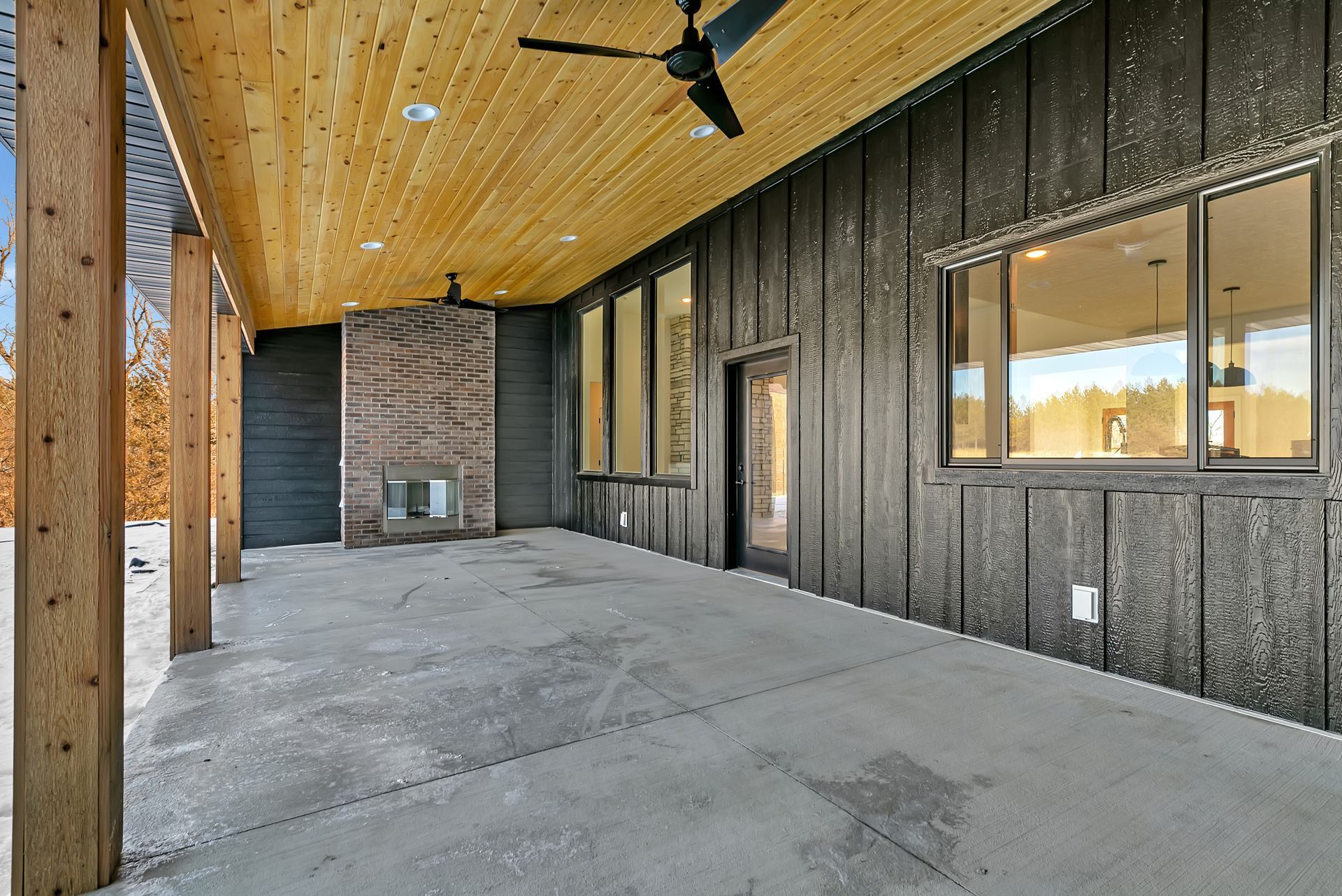 A large covered patio with a fireplace and ceiling fan.