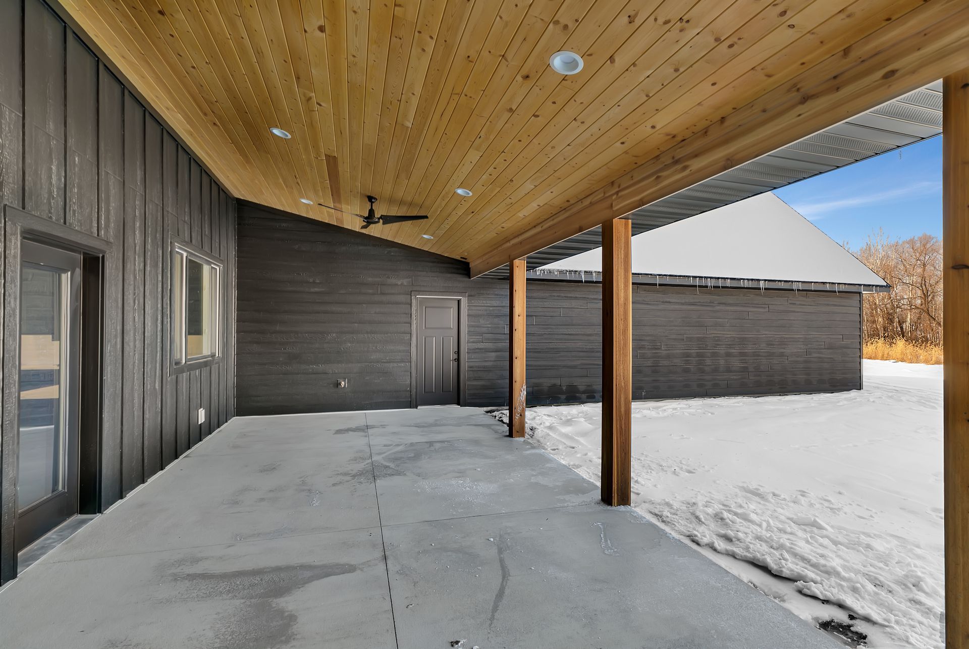 A large covered patio with a wooden ceiling and a ceiling fan.