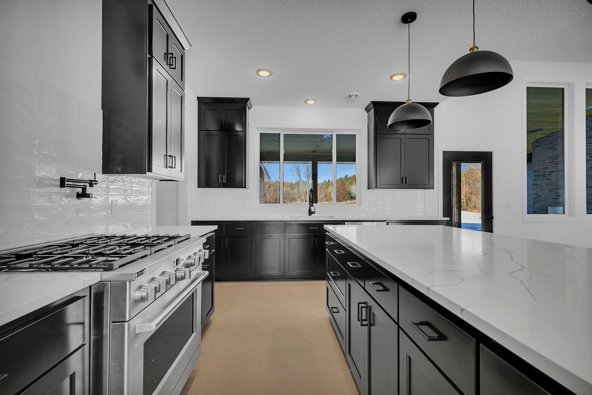 A kitchen with black cabinets , stainless steel appliances , and a large island.
