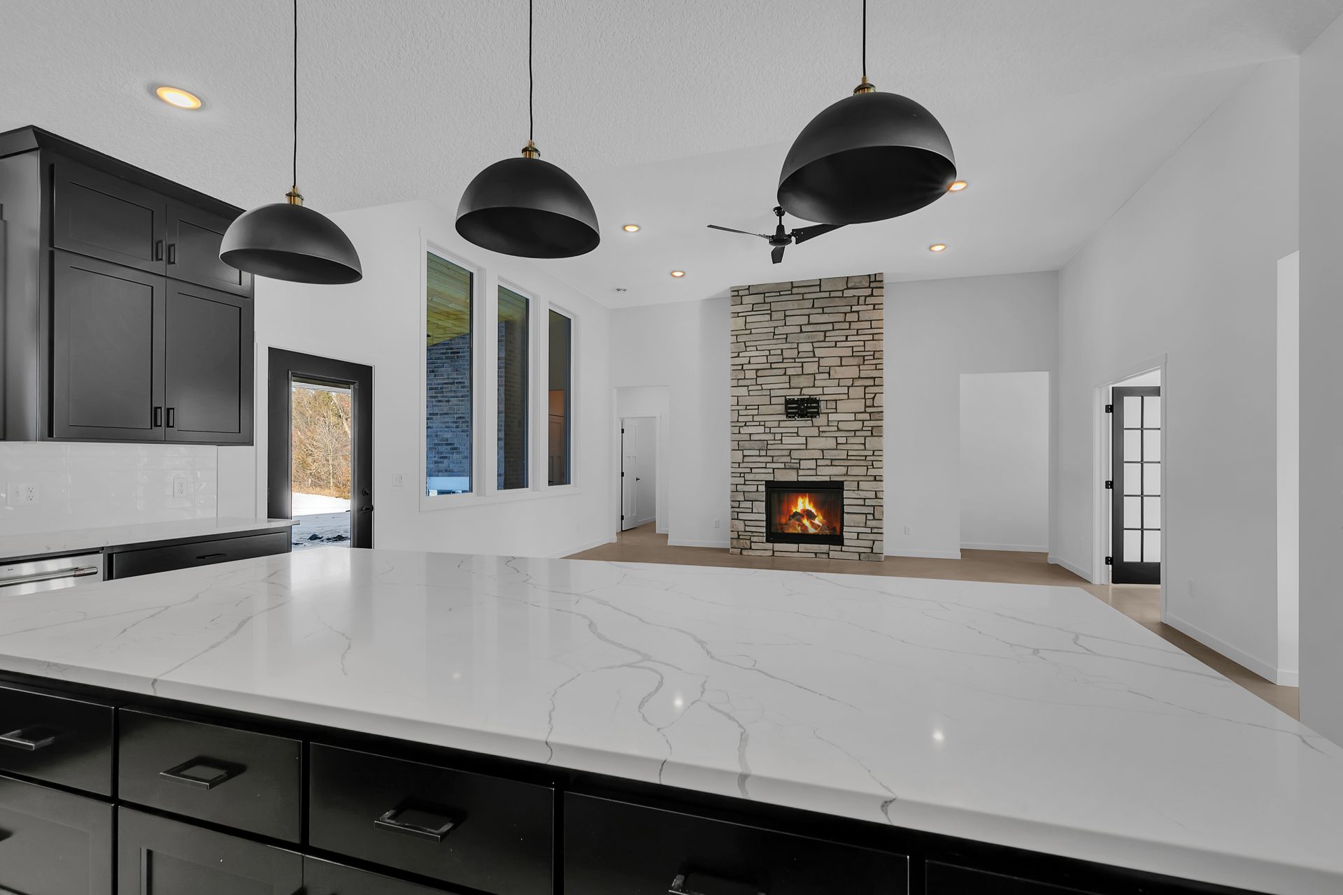 A kitchen with black cabinets and white counter tops and a fireplace.