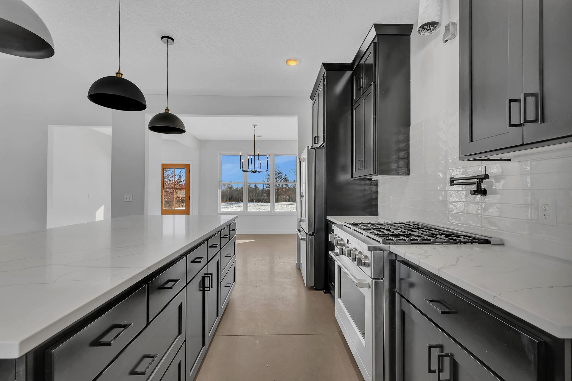 A kitchen with black cabinets , white counter tops , stainless steel appliances and a large island.