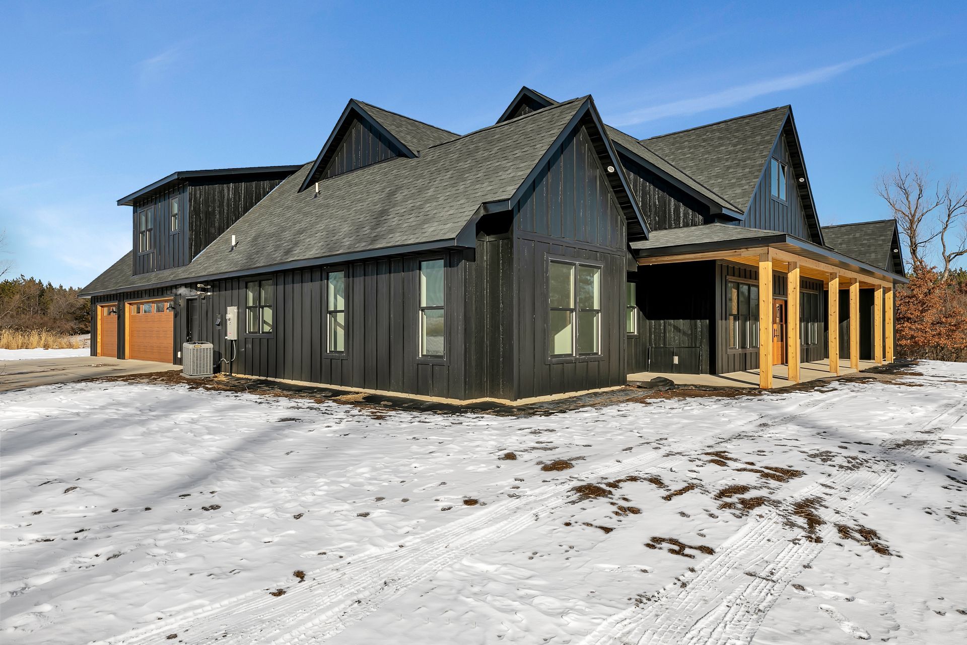 A large black house is sitting in the middle of a snow covered field.