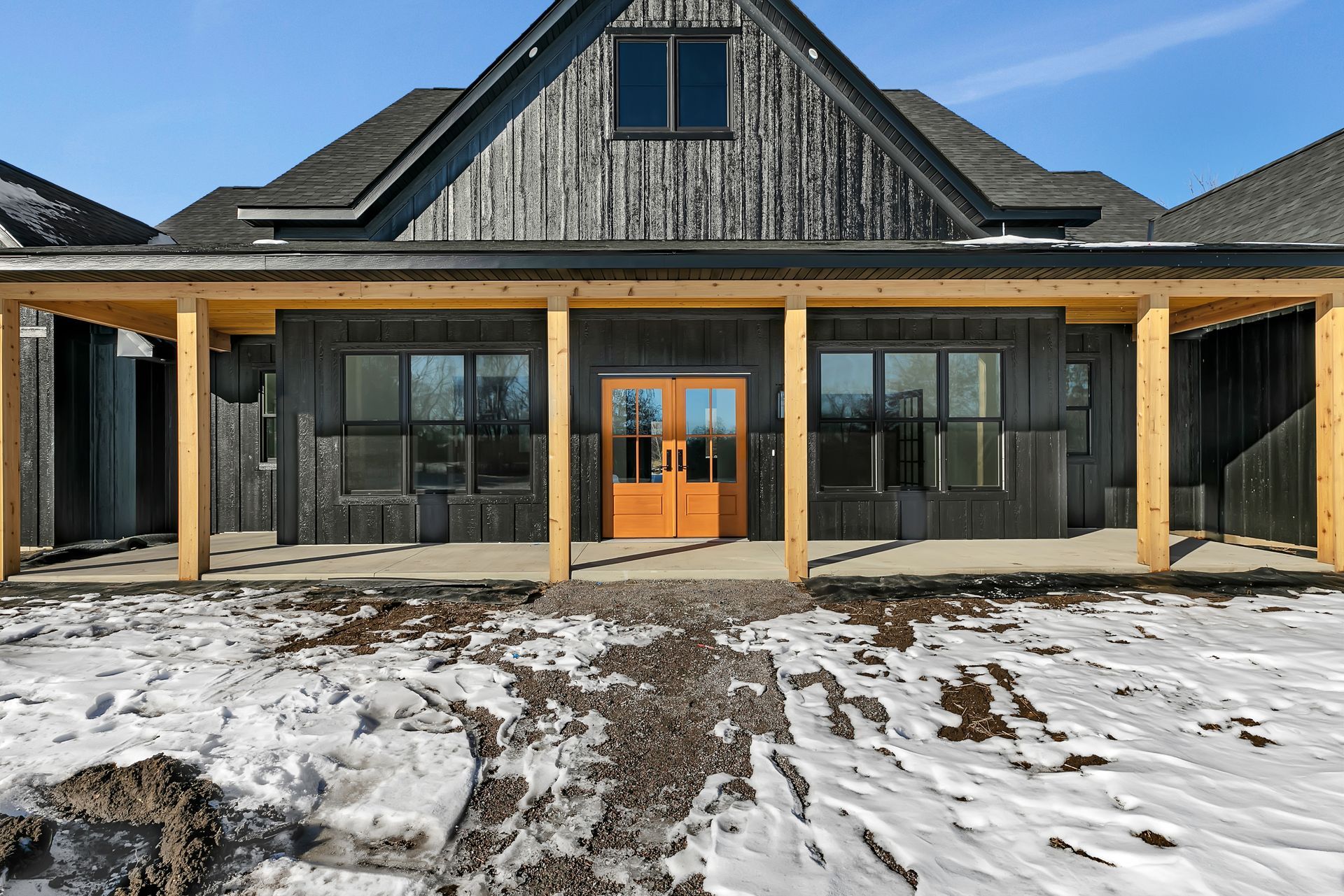 A large house with a porch and a wooden door in the snow.