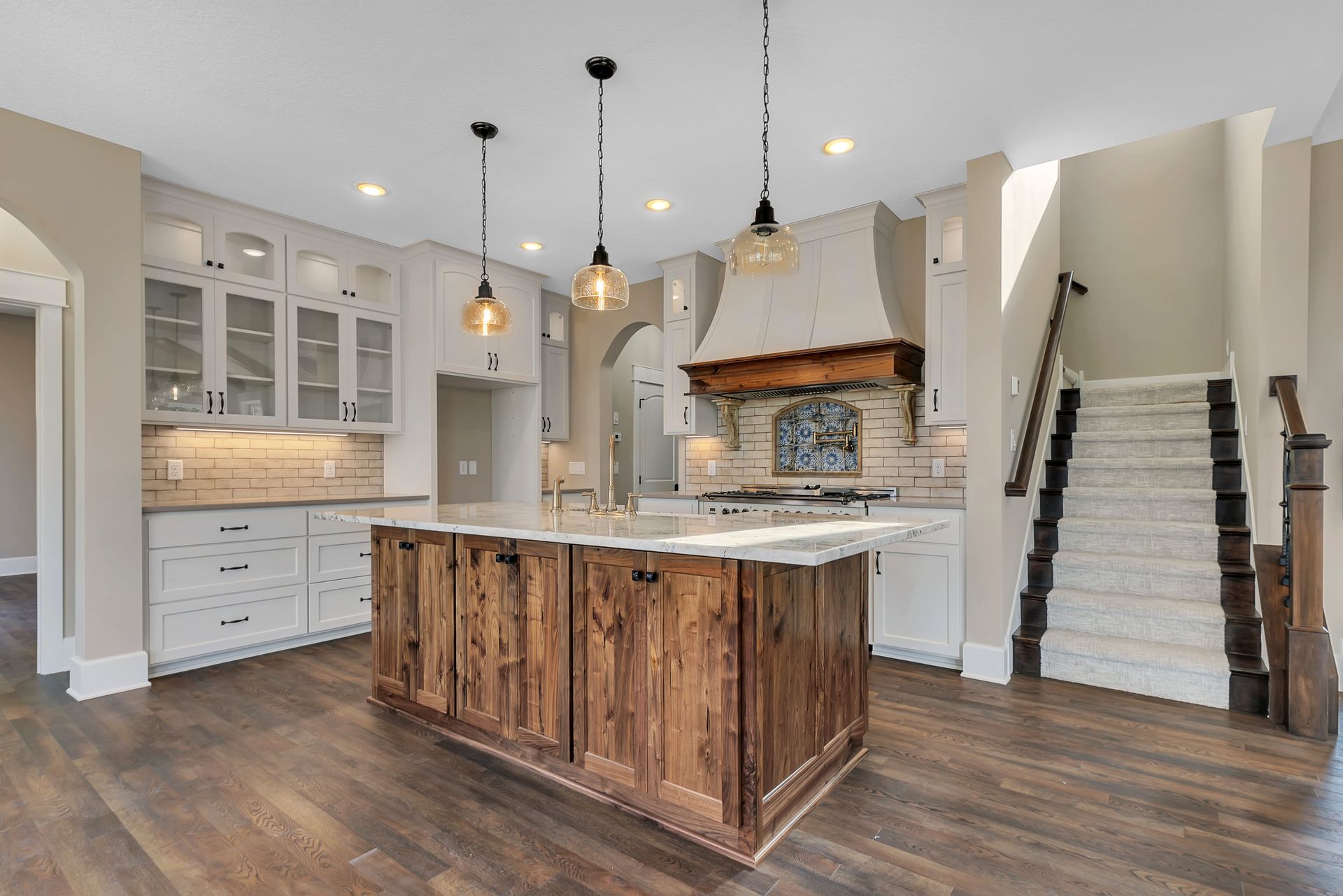 A kitchen with a large wooden island and stairs.
