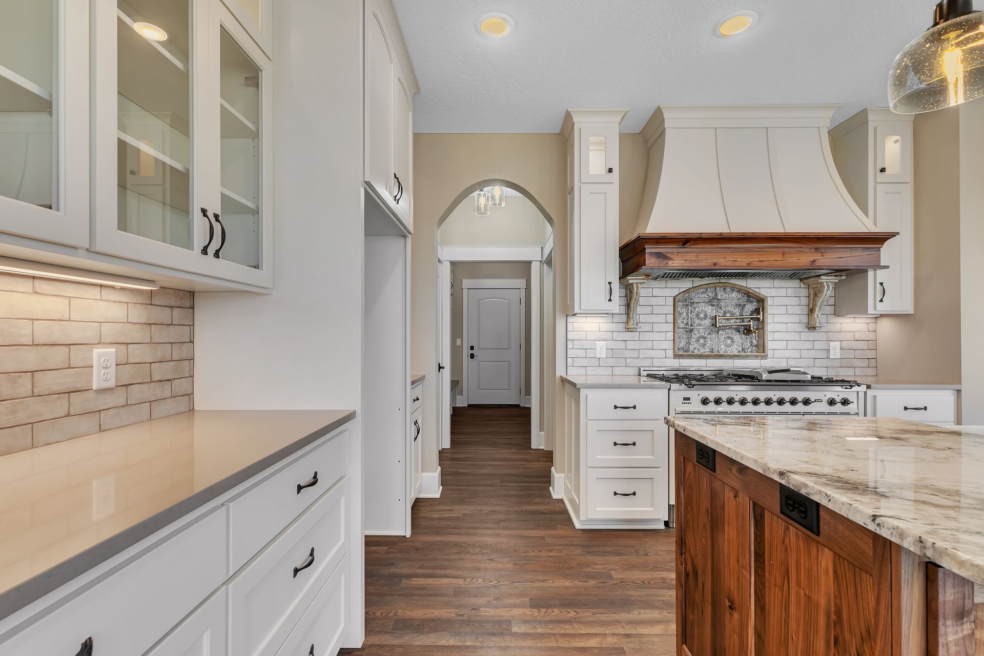 A kitchen with white cabinets , granite counter tops , and a large island.