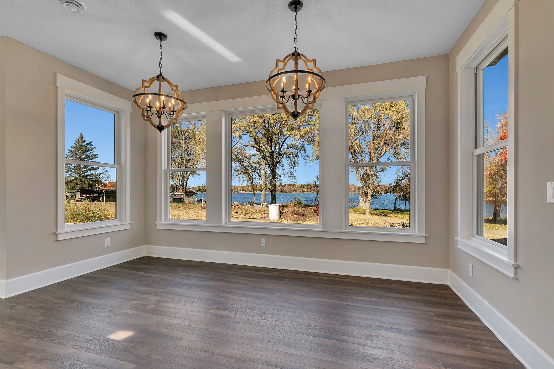An empty room with a lot of windows and a view of a lake.