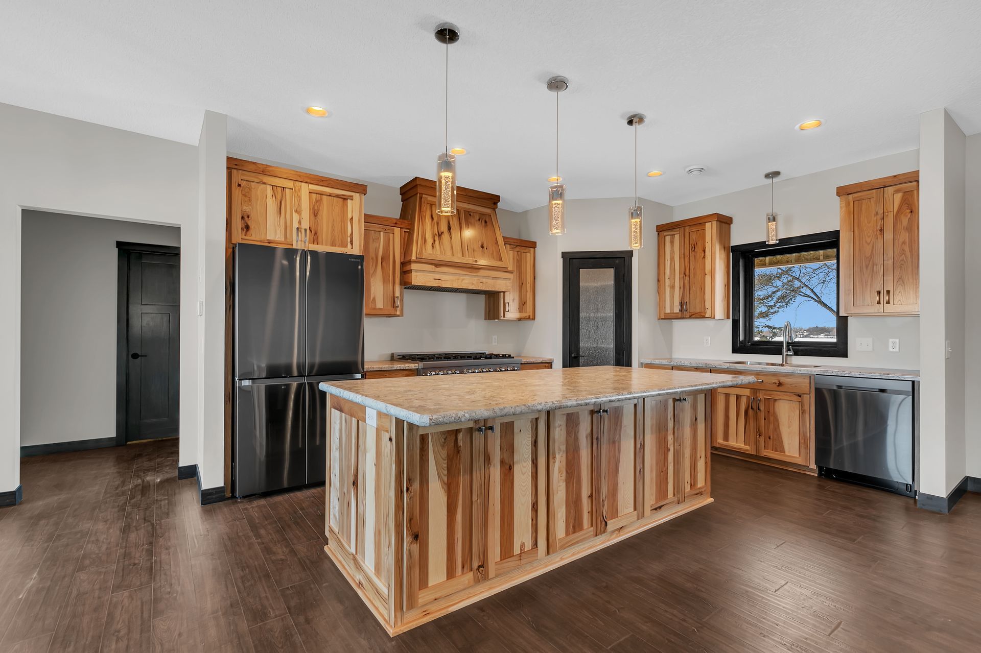 A kitchen with wooden cabinets , stainless steel appliances , and a large island.