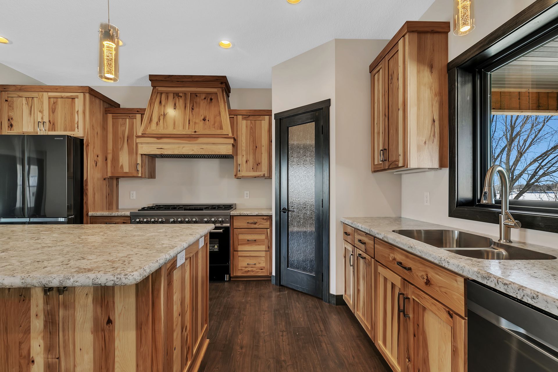 A kitchen with wooden cabinets , granite counter tops , stainless steel appliances and a large island.