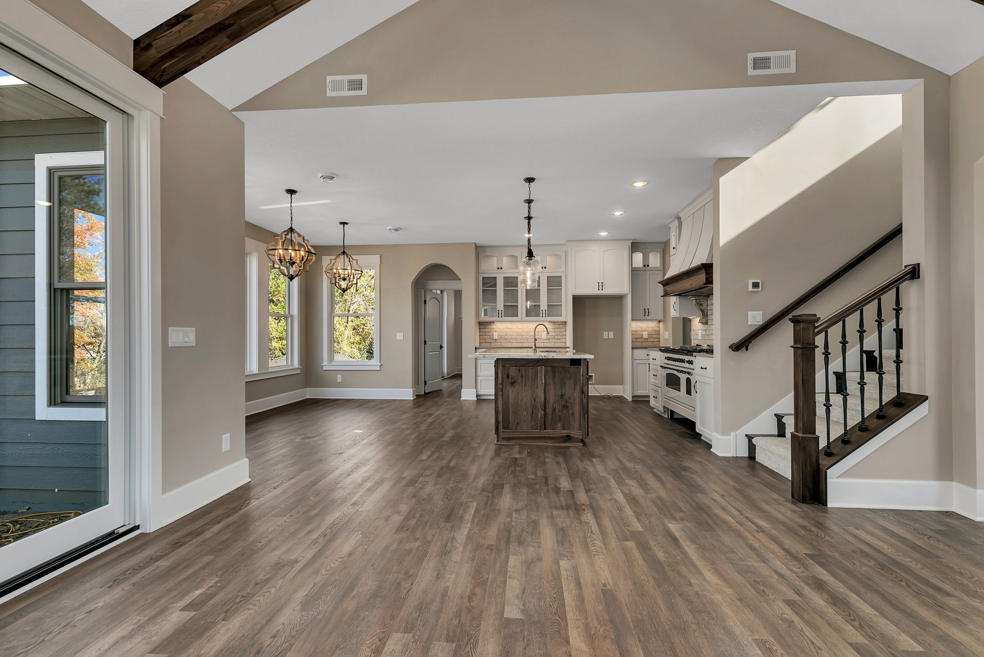 A living room with hardwood floors and a kitchen in a house.