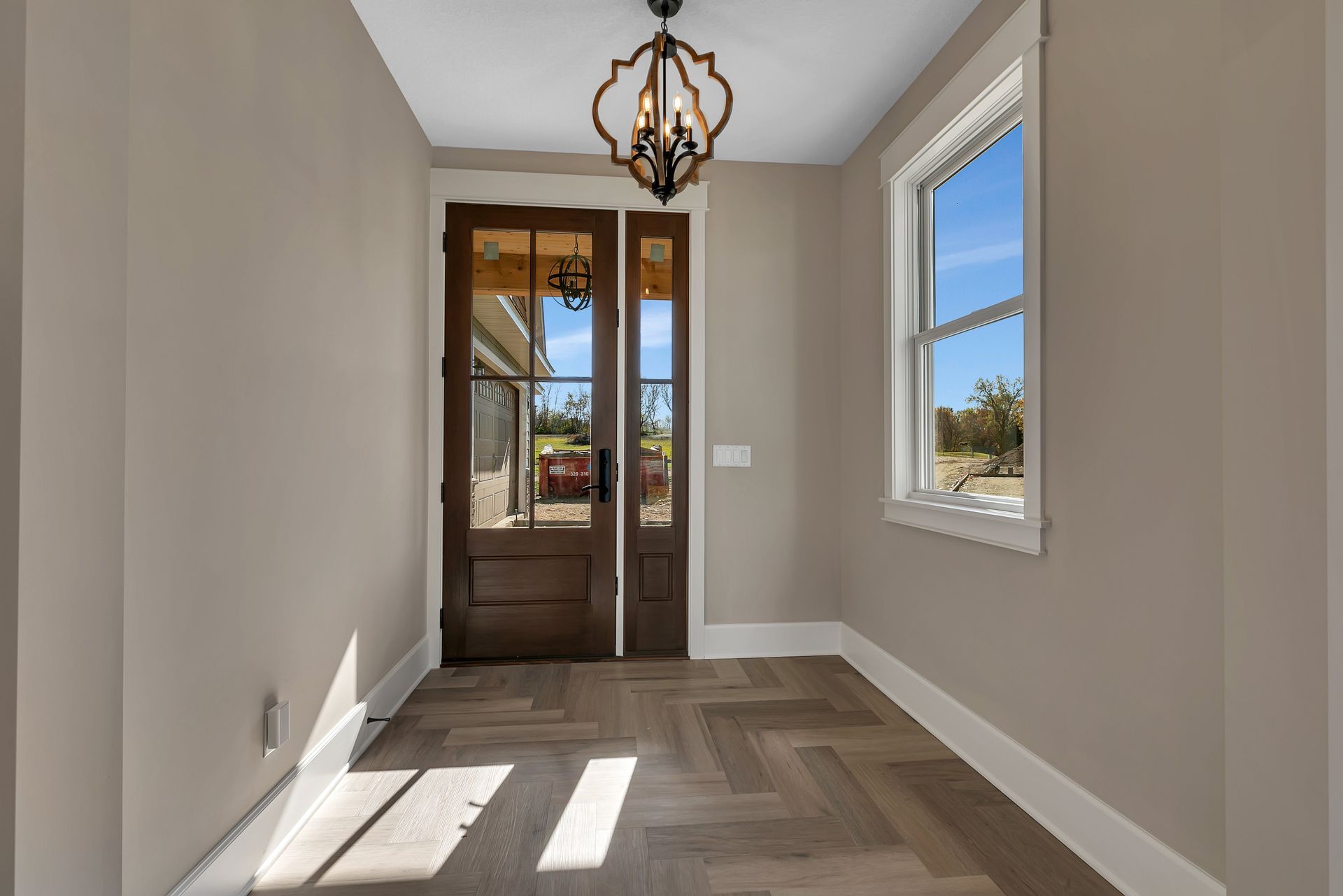 An empty hallway with a wooden floor and a chandelier hanging from the ceiling.